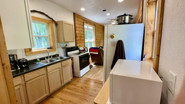 kitchen featuring light hardwood / wood-style floors, sink, wooden walls, white appliances, and light brown cabinetry