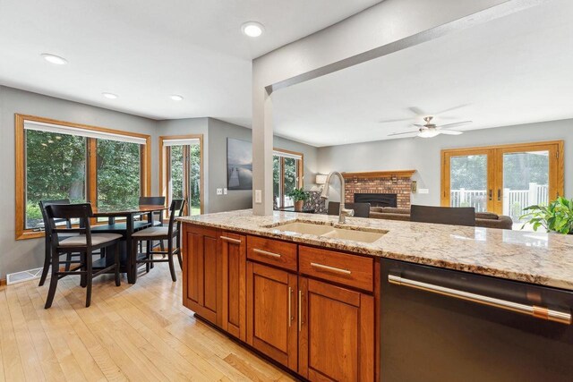 S2916A Fairway Dr, Reedsburg, WI 53959 - kitchen featuring a brick fireplace, light hardwood / wood-style flooring, dishwashing machine, light stone countertops, and sink