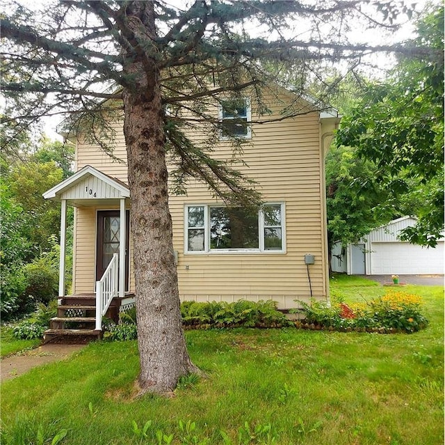 view of front facade with an outbuilding, a garage, and a front lawn