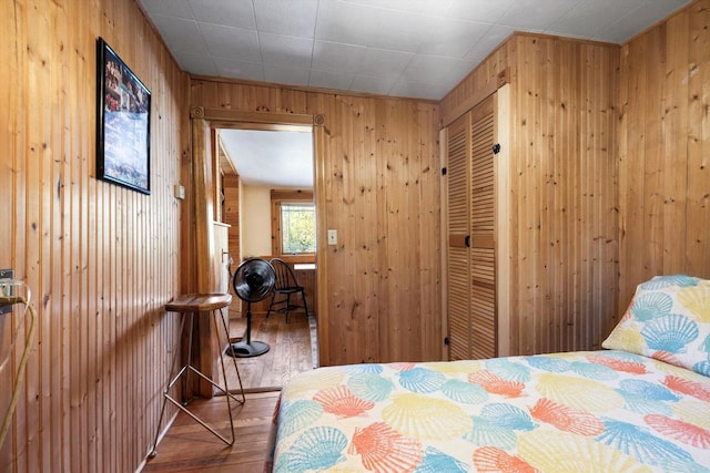 bedroom featuring hardwood / wood-style flooring, wooden walls, and a closet