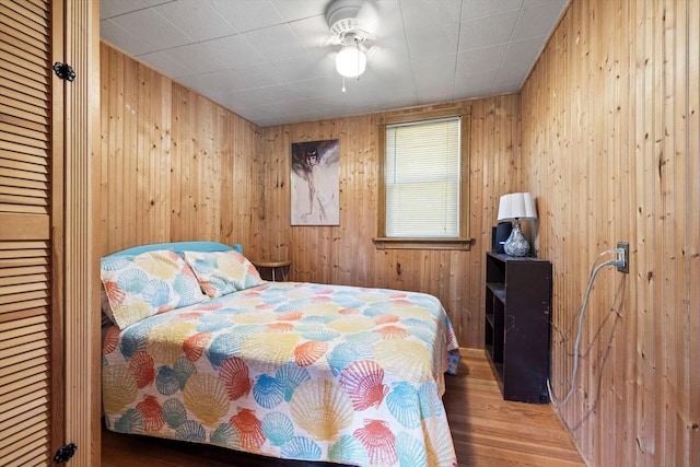 bedroom featuring ceiling fan, wooden walls, and hardwood / wood-style floors