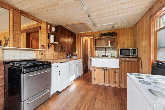 kitchen with wood walls, rail lighting, white cabinets, dark hardwood / wood-style flooring, and white appliances