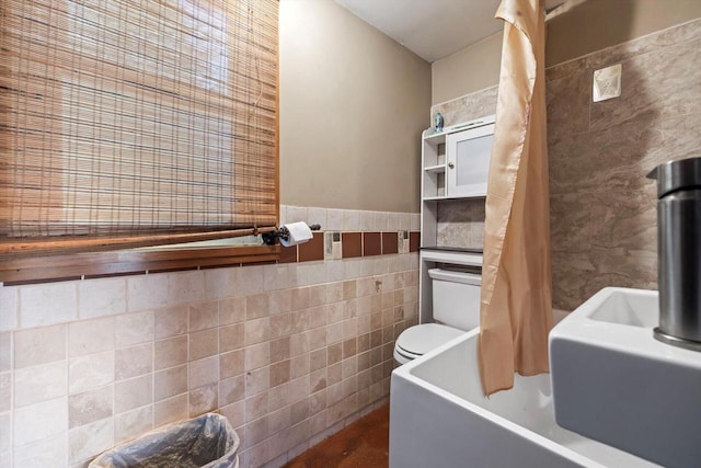 bathroom featuring tile walls, toilet, and a bathtub