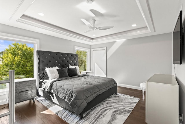 bedroom with ceiling fan, a tray ceiling, and dark wood-type flooring