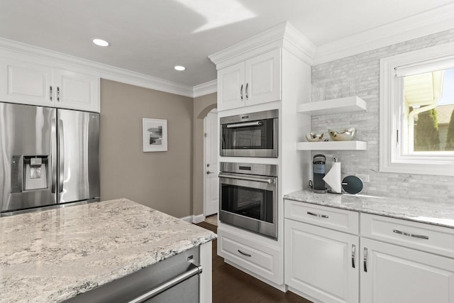 kitchen with appliances with stainless steel finishes, decorative backsplash, white cabinets, light stone countertops, and dark hardwood / wood-style flooring