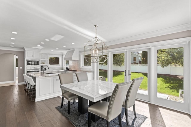 dining room with dark wood-type flooring, plenty of natural light, sink, and crown molding