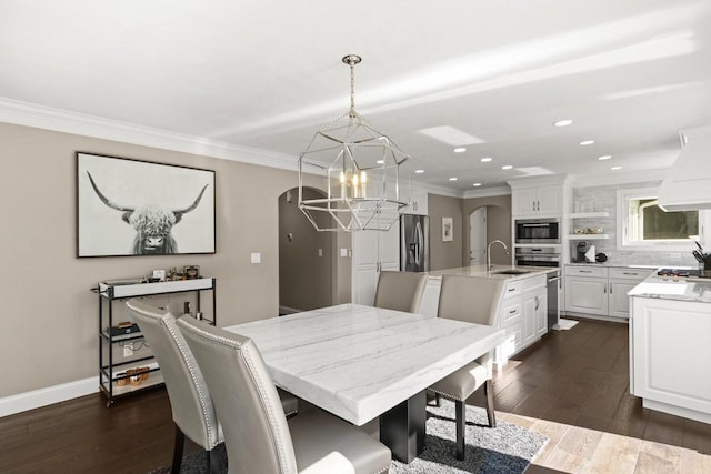 dining room with a notable chandelier, sink, dark hardwood / wood-style floors, and crown molding