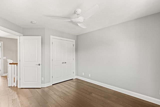 unfurnished bedroom with ceiling fan, a closet, and hardwood / wood-style floors