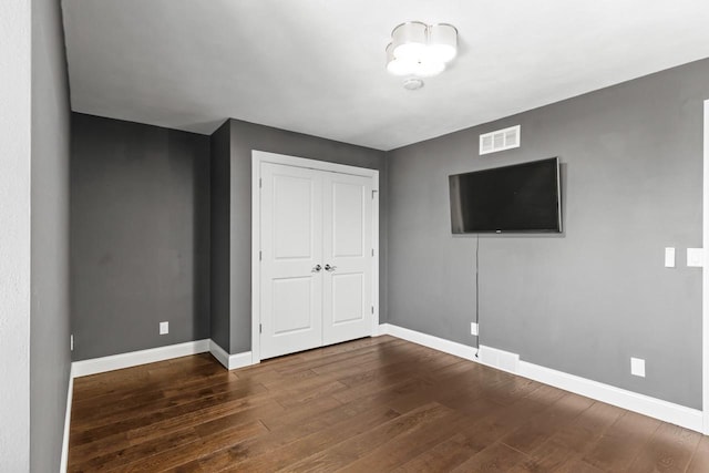 unfurnished bedroom featuring a closet and dark wood-type flooring