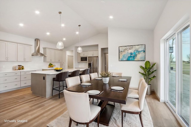 dining space featuring light hardwood / wood-style flooring, sink, and vaulted ceiling