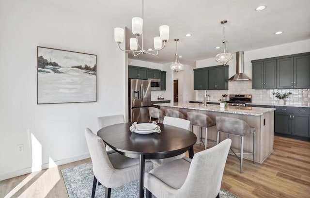 dining space featuring light wood-type flooring, sink, and a notable chandelier