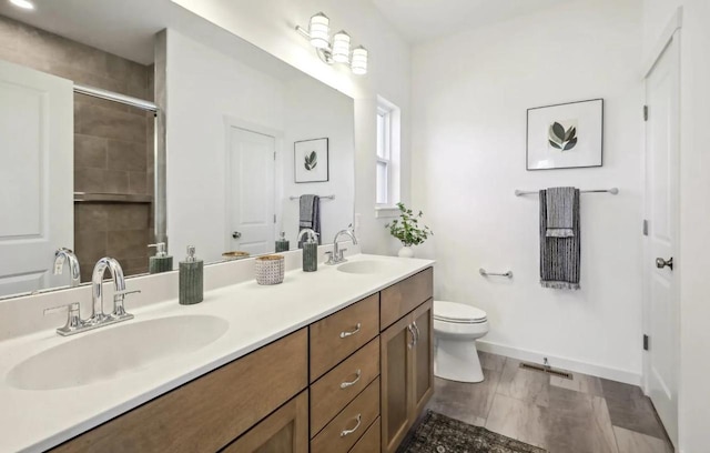 bathroom with hardwood / wood-style floors, vanity, toilet, and a shower with door