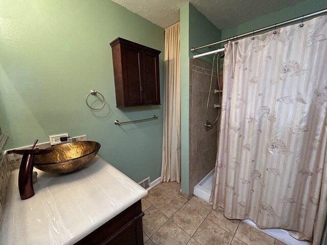 bathroom with a textured ceiling, vanity, a shower with shower curtain, and tile patterned floors