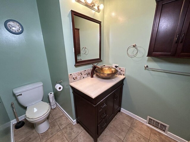 bathroom with toilet, vanity, tile patterned flooring, and tasteful backsplash