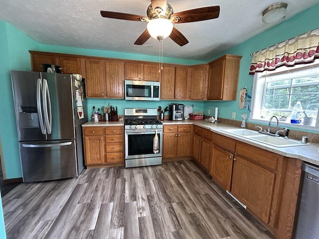 kitchen featuring appliances with stainless steel finishes, dark hardwood / wood-style floors, sink, a textured ceiling, and ceiling fan