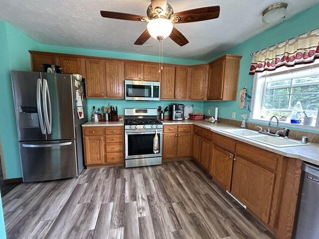 kitchen featuring hardwood / wood-style flooring, stainless steel appliances, sink, ceiling fan, and a textured ceiling