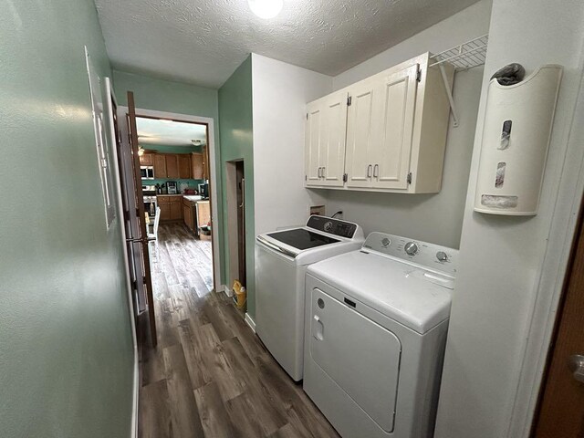 laundry room featuring cabinets, washing machine and dryer, dark hardwood / wood-style flooring, and a textured ceiling