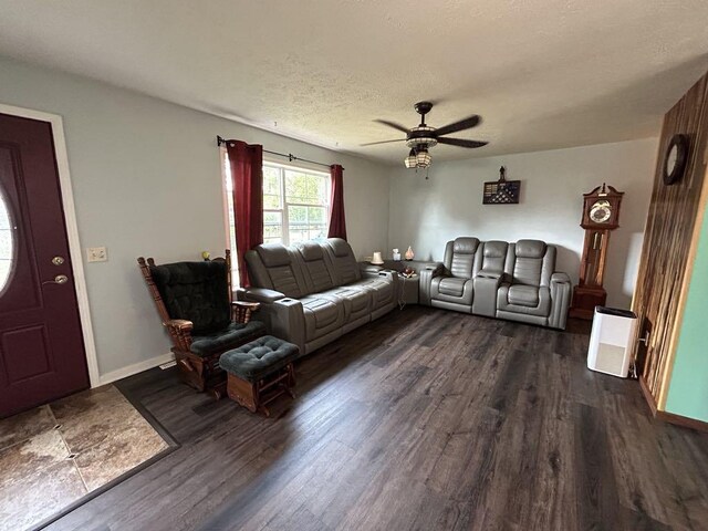 living room featuring ceiling fan, dark wood-type flooring, and a textured ceiling