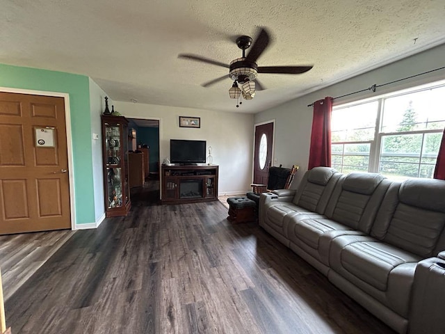 living room with a textured ceiling, ceiling fan, and dark hardwood / wood-style floors