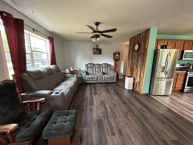 living room with a textured ceiling, ceiling fan, and dark hardwood / wood-style flooring