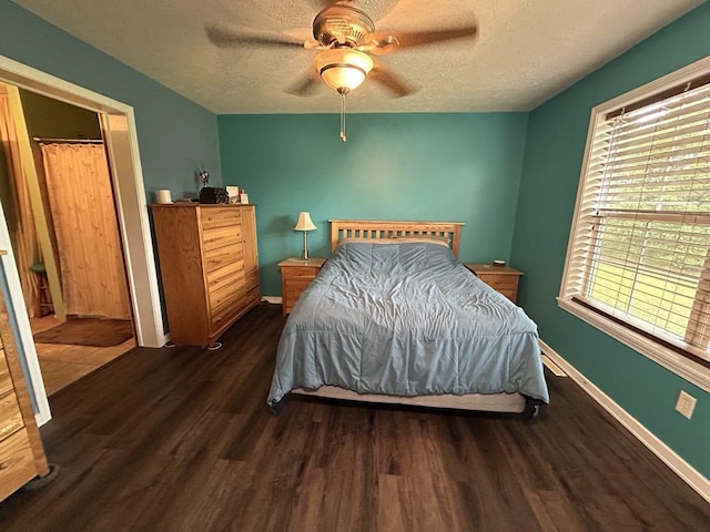 bedroom with ceiling fan, dark wood-type flooring, and a textured ceiling