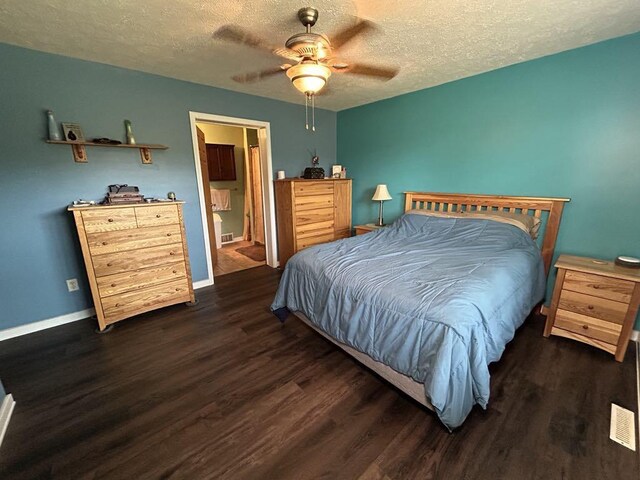 bedroom featuring ceiling fan, ensuite bath, dark hardwood / wood-style flooring, and a textured ceiling