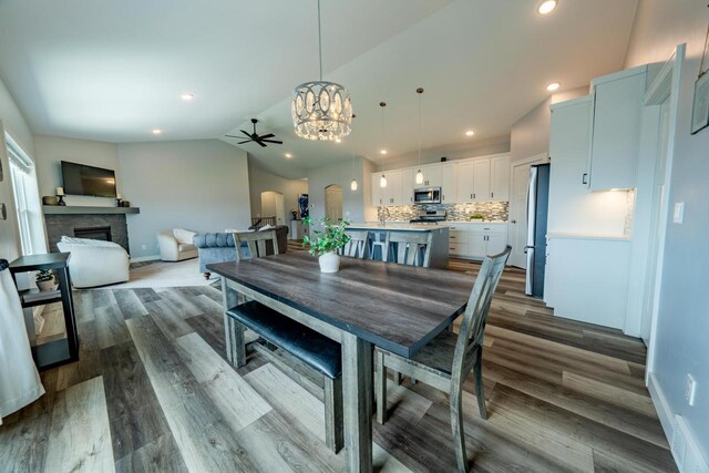 dining area featuring hardwood / wood-style flooring, vaulted ceiling, and ceiling fan with notable chandelier