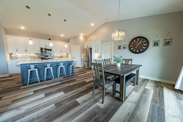 dining area featuring hardwood / wood-style flooring, high vaulted ceiling, and an inviting chandelier