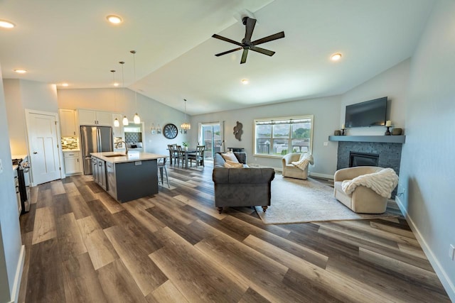 living room with a fireplace, sink, ceiling fan, high vaulted ceiling, and dark hardwood / wood-style floors