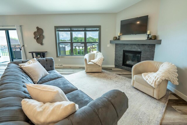 living room with light wood-type flooring and a stone fireplace