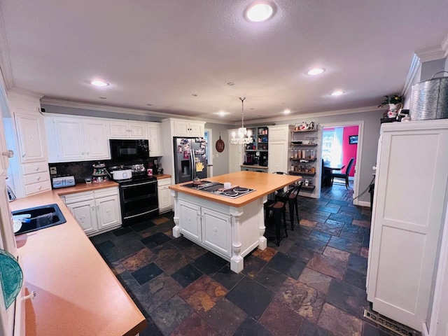 kitchen with white cabinetry, a center island, hanging light fixtures, black appliances, and sink