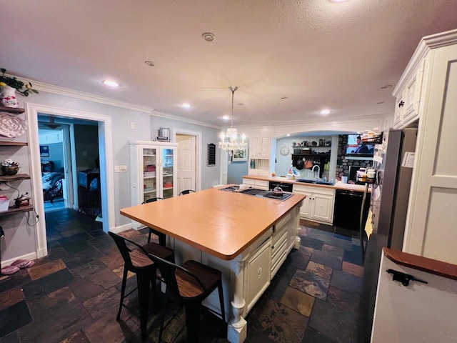 kitchen with black appliances, decorative light fixtures, a breakfast bar, a center island, and sink