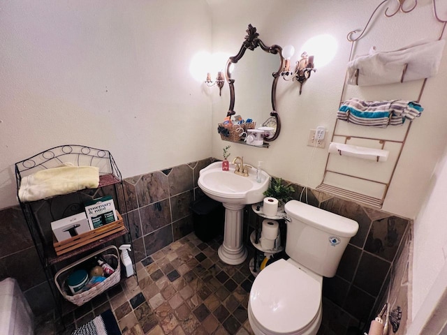 bathroom featuring toilet and tile walls