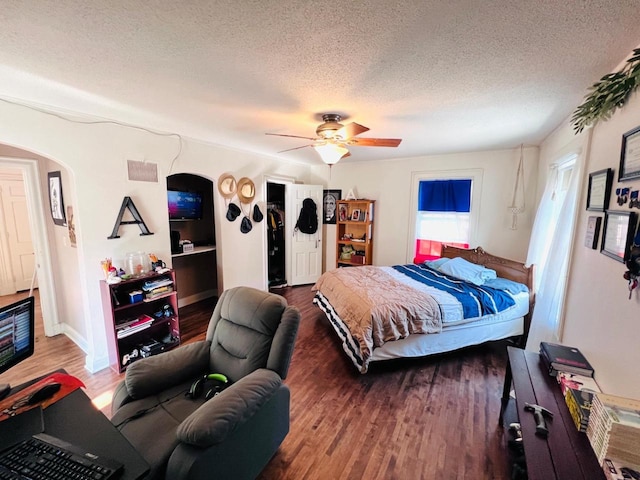 bedroom with a textured ceiling, ceiling fan, and wood-type flooring