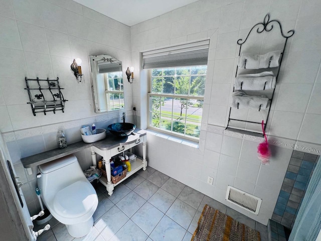 bathroom with tile walls, toilet, and tile patterned floors