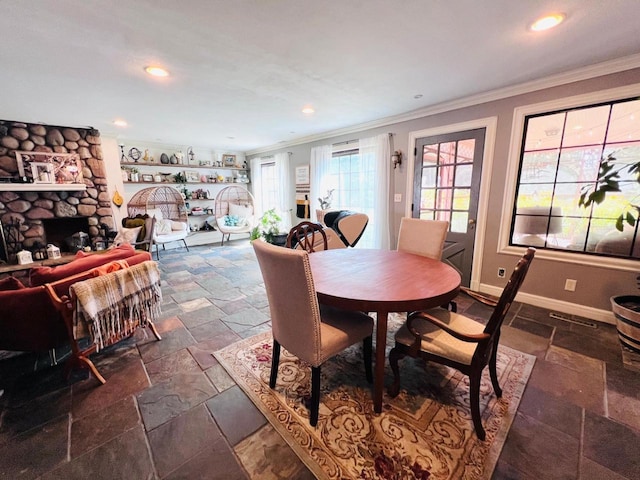 dining space with ornamental molding and a fireplace