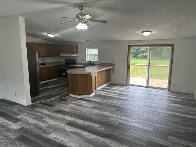 kitchen featuring dark hardwood / wood-style flooring, stainless steel refrigerator, a textured ceiling, ceiling fan, and stove