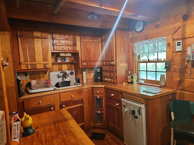 kitchen with refrigerator, sink, butcher block counters, and wood walls