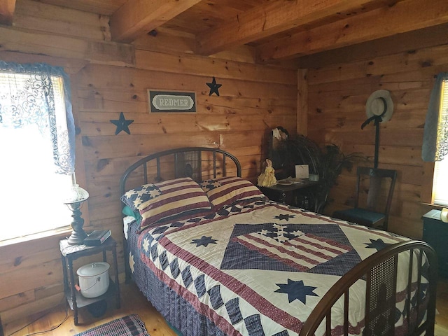 bedroom featuring beamed ceiling and wood walls