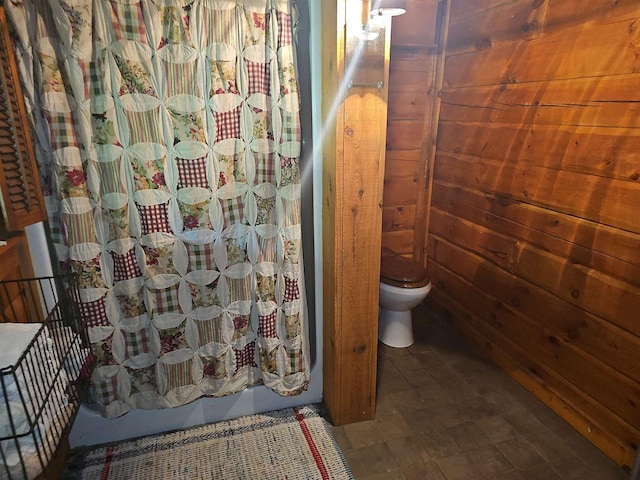 bathroom featuring toilet and wood walls