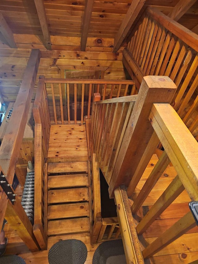 staircase with beamed ceiling, wooden ceiling, and wood walls