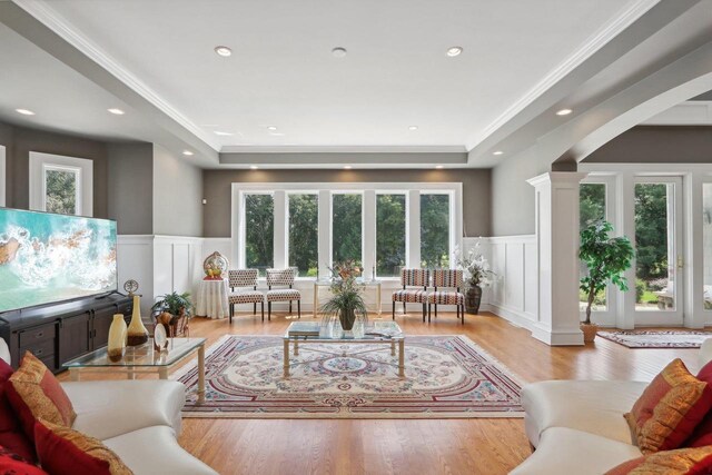 dining area with light wood-type flooring, a premium fireplace, ornate columns, and ornamental molding