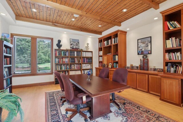 living room with a wealth of natural light, light wood-type flooring, decorative columns, and a tray ceiling