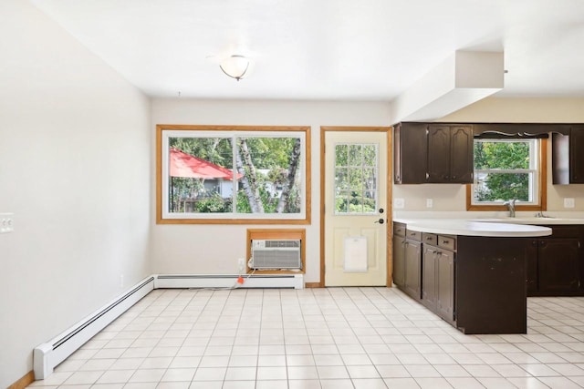 kitchen with dark brown cabinets, baseboard heating, and a wealth of natural light