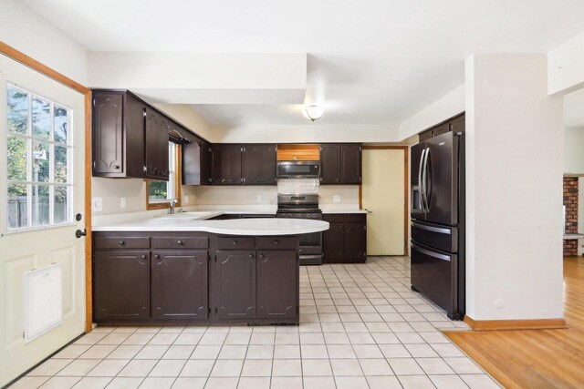 kitchen featuring appliances with stainless steel finishes, kitchen peninsula, dark brown cabinets, and sink