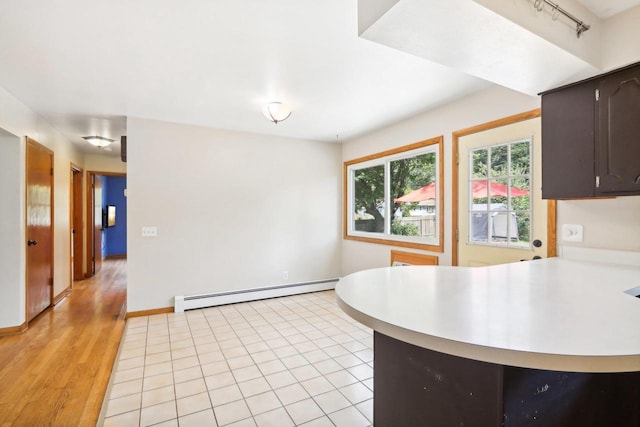 kitchen featuring a baseboard radiator, light wood-type flooring, kitchen peninsula, and dark brown cabinetry