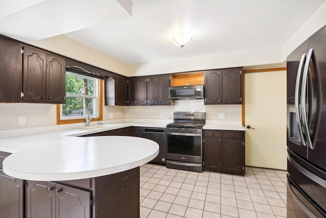 kitchen with dark brown cabinetry, appliances with stainless steel finishes, sink, and kitchen peninsula