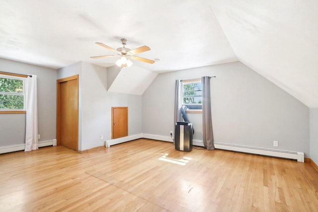 additional living space with a baseboard radiator, light wood-type flooring, a wealth of natural light, and ceiling fan