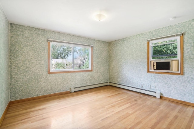 spare room with a baseboard heating unit, wood-type flooring, and a healthy amount of sunlight