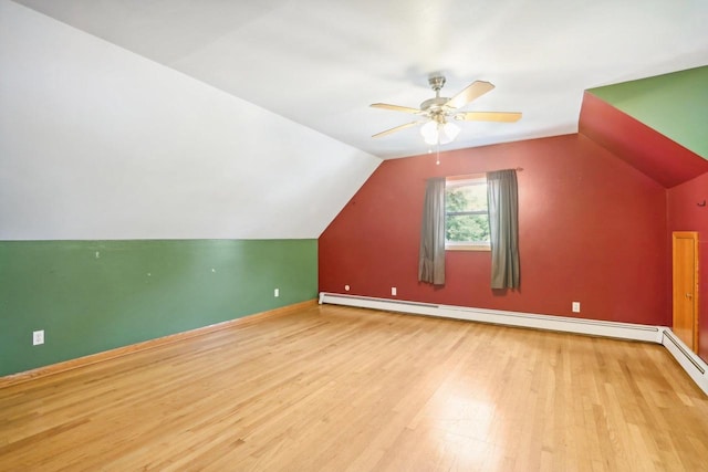 additional living space with light wood-type flooring, lofted ceiling, a baseboard heating unit, and ceiling fan